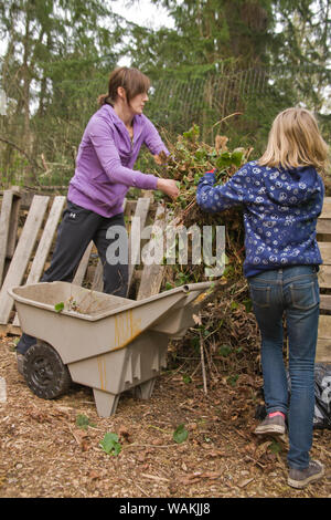 Issaquah, Washington State, USA. Frau und Tochter werfen Erdbeerpflanzen auf Kompost-haufen. (MR, PR) Stockfoto