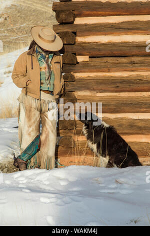 Cowboy Pferd Antrieb auf Versteck Ranch, Shell, Wyoming. Cowgirl lehnte sich gegen die Kabine mit ihrer Ranch Hund anmelden. (MR) Stockfoto