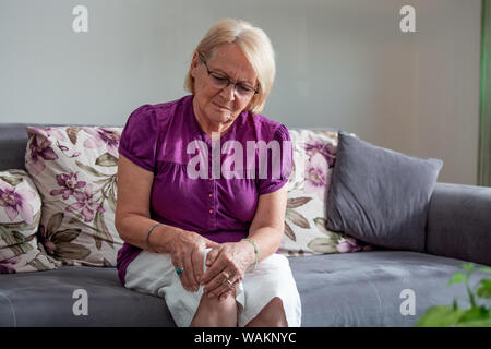 Alter, Gesundheit Problem und Personen Konzept - ältere Frau leiden unter Schmerzen im Bein zu Hause. Ältere Frau mit dem Knie mit Schmerzen. Stockfoto
