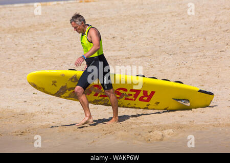 Rettungsschwimmer mit Surfbrett-Rettungsschlitten in Branksome Chine, Poole, Dorset UK an einem warmen sonnigen Tag im August Stockfoto