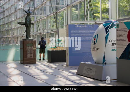 Riesige Rugby World Cup 2019 rugby ball Monument, das sich in der Tokyo International Forum mit Statue von Samurai Warrior Ota Doukan im Hintergrund. (9/2019) Stockfoto