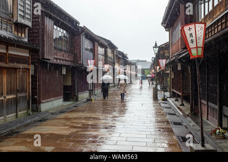 Touristen wandern mit Sonnenschirmen im Regen letzten traditionellen Teehäuser und Gebäuden in der higashi Chaya geisha Bezirk, Kanazawa, Japan Stockfoto