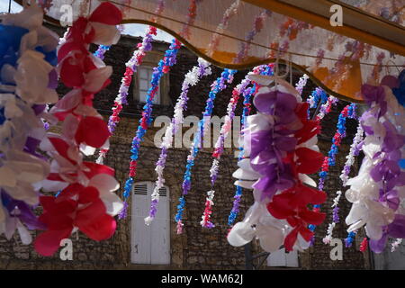 Einen teilweisen Blick auf einem traditionellen Stein French House durch Flower Festival Dekorationen hängen von einem Shop Markise Stockfoto