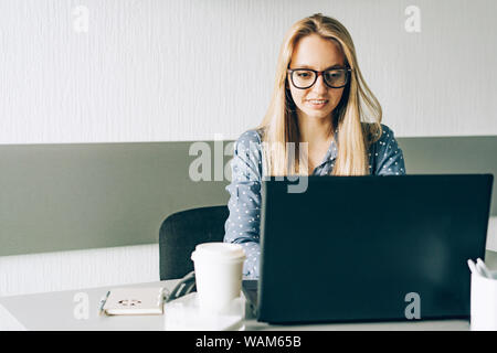 Blondine mit Brille arbeiten am Laptop im Büro Stockfoto