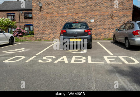 Autos Auto geparkt in ausgewiesenen Behindertenparkplätzen Platz mit Rollstuhl Symbol England UK Vereinigtes Königreich GB Großbritannien Stockfoto