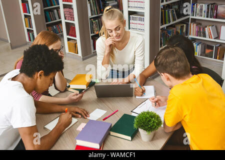 Studierende sammeln im Kreis, gemeinsam Hausaufgaben machen Stockfoto