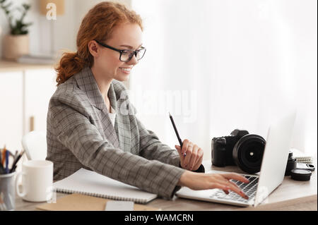 Fotograf aus Laden von Dateien auf dem Laptop im Büro Stockfoto
