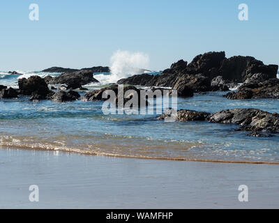 Seascape, das wunderschöne Farben von Blau und Sand einfängt, Wellen, die auf Felsen krachen, während sie in den Strand Rollen Stockfoto