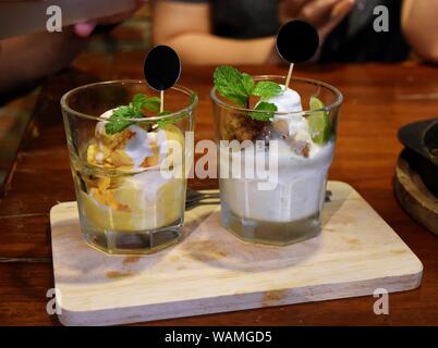 Zwei Glas Eis auf einem hölzernen Fach, süßen und erfrischenden Geschmack von Durian Frucht und Kokosmilch dekoriert Limette und Minze, Thailand Stockfoto