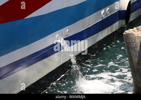 Wasser, das aus dem Schiff gepumpt wurde, während an der Pier geparkt. Wasser, das aus dem Schiff aufgenommen wurde. Stockfoto