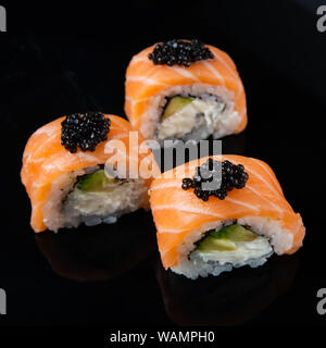 Sushi Roll Philadelphia mit Lachs, geräucherter Aal, Avocado, Frischkäse auf schwarzem Hintergrund. Japanisches Essen Stockfoto