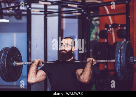 Muskulöse Mann heraus in der Turnhalle, die Übungen mit Barbell bei bizeps Stockfoto