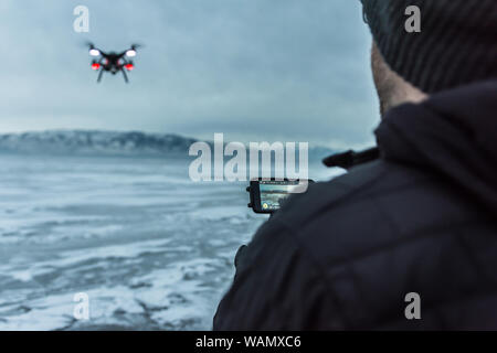 Über die Schulter geschossen der kaukasischen männlichen Fliegen quadcopter über Utah Lake, USA eingefroren Stockfoto