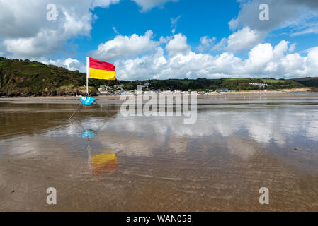 Eine rote und gelbe lebensrettende Flagge gegen einen bewölkten Himmel Setup von Rettungsschwimmern in Pendine, Wales Stockfoto