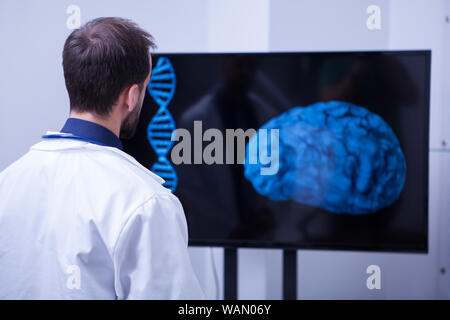 Junger Gehirnchirurg lookin eine dieser Patient Gehirn aftter die Chirurgie. Arzt mit moder Technologie aus dem Krankenhaus. Stockfoto