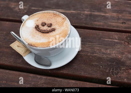 Nahaufnahme von einer Tasse Kaffee mit einem Lächeln im Gesicht, außerhalb in einer britischen Beach Holiday Resort, Pendine Wales Stockfoto