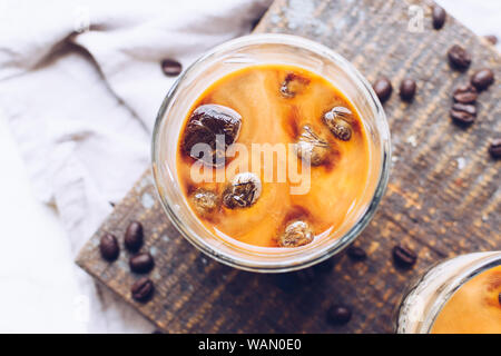 Kaffee Espresso mit Milch Eiswürfel im Glas auf weißem Hintergrund. Kalten Sommer Getränke. Ansicht von oben. Close Up. Stockfoto