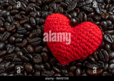 Rotes Herz auf eine Menge von gerösteten Kaffeebohnen Hintergrund. Starken schwarzen Kaffee Espresso, Körner, Hintergrund, Textur Stockfoto