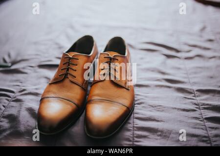 Nahaufnahme von braunen klassischen Schuhen auf einem grauen Laken Stockfoto