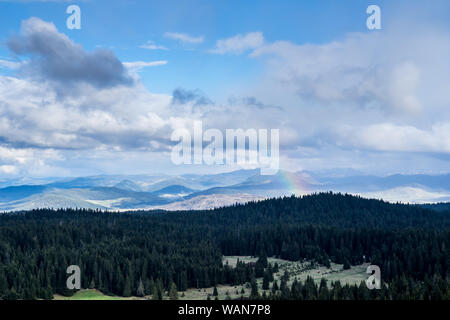 Montenegro, bunten Regenbogen über schwarzen Nadelbäume der alpinen Wald auf Hochland von durmitor Nationalpark Natur Landschaft im Morgengrauen von den Bergen oben Stockfoto