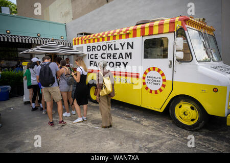 Die Besucher der Dumbo Nachbarschaft von Brooklyn in New York genießen Sie kostenfreien Mini-Kegel von der Brooklyn Ice Cream Factory am Sonntag, 11. August 2019. Früher auf Pier One in Brooklyn Bridge Park das Eis Hoflieferant von weiten Hügeln Creamery ersetzt wurde und wird in den Prozess der Einrichtung ihren festen Standort in der Nähe. Brooklyn Ice Cream Factory hat die restaurierte Feuerlöschboot Haus, wo es seit 2001 besetzt. (© Richard B. Levine) Stockfoto