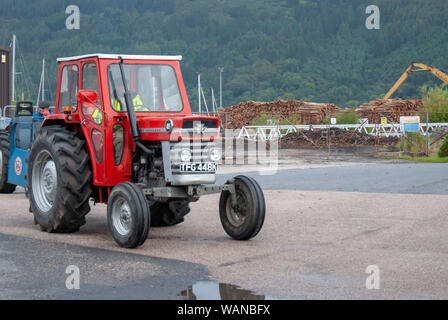 Mann Gelb Jacke fahren Rot Grau 1972 Vintage Massey Ferguson 185 Traktor mit Rot Weiß Cab männlichen fluoreszierend Wasserdicht abseits vorne Fahrerseite Stockfoto