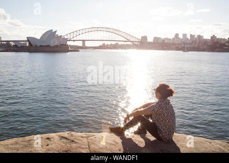 Junger Mann mit lockigem Haar, in den Hafen von Sydney, während Golden Sunset Stockfoto