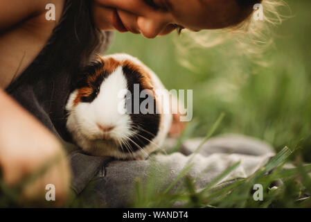 Kleines Mädchen ihr Haustier Meerschweinchen kuscheln im Gras Stockfoto