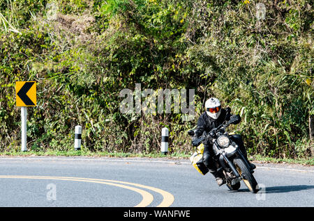 Mann auf Scrambler Art Motorrad reiten durch Drehen in Nord Thailand Stockfoto