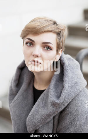 Frau mit kurzen stilvolle Frisur im grauen Mantel auf weißem Hintergrund Stockfoto