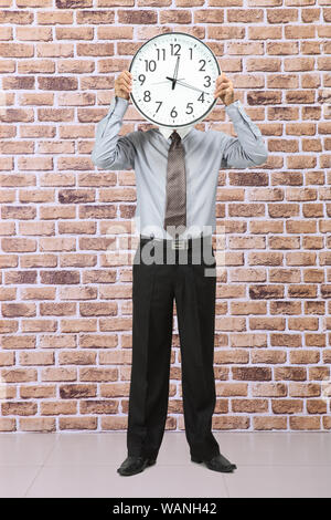 Unternehmer, die eine Uhr vor seinem Gesicht halten Stockfoto