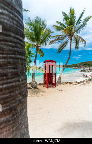Red britische Telefonzelle vor der klaren Karibischen Meer, Siboney Beach, Dickenson Bay, Antigua Stockfoto