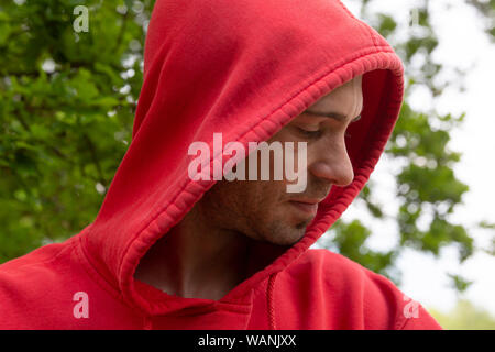 Portrait von jungen Mann mit Rot hoodie Suche wirklich ernste Stockfoto