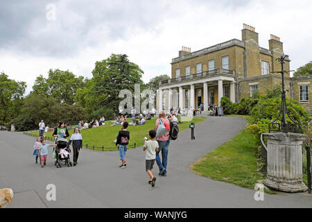 Familien Flanieren auf dem Weg außerhalb Clissold Haus und das Sitzen auf dem Rasen in Clissold Park im Sommer Stoke Newington London UK KATHY DEWITT Stockfoto