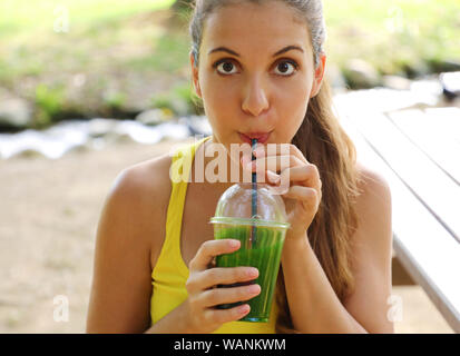 Nahaufnahme von Fitness Mädchen an Kamera und trinken grünen detox Saft in den Park. Stockfoto