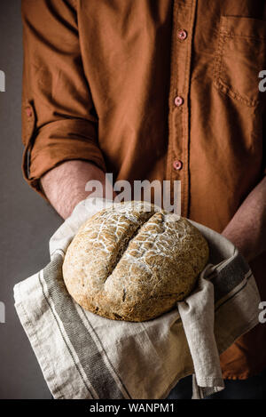 Mann hält ein Laib von frisch gebackenem Roggenbrot Stockfoto
