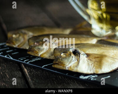 Geräucherter Fisch und Bier auf Holz- Hintergrund. Seitenansicht Stockfoto