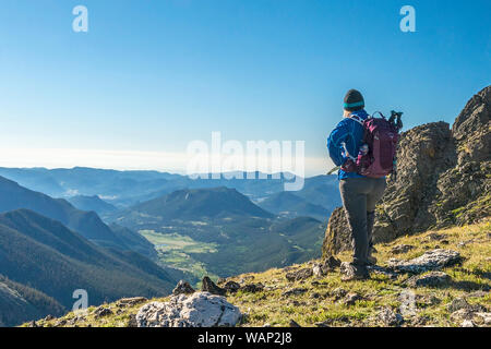 Eine weibliche Wanderer hält auf dem Gipfel des Mount Chapin in der Ansicht von Estes Park im Osten im Rocky Mountain National Park, Colorado. Stockfoto