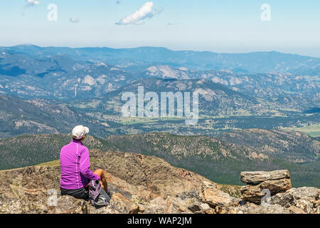 Eine weibliche Wanderer mit Blick auf die westlichen Täler der Rocky Mountain National Park, während Sie entlang der Flattop Mountain Trail. Stockfoto