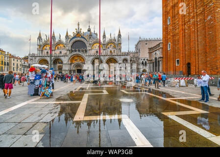 Touristen Menge St. Mark's Platz vor der Basilika nach einem Hochwasser, da das Wasser sich zurückbilden, in Venedig, Italien beginnt Stockfoto