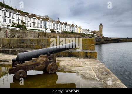 Canon Relikt auf Stein Pier der Porthleven Hafen mit Bickford Smith Institut Porthleven Stadtrat Gebäude auf dem Atlantischen Ozean Cornwall England Stockfoto