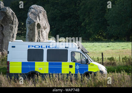 Avebury, Wiltshire, UK. 21. August 2019. Einen Polizeiwagen geht durch das Weltkulturerbe von Avebury, der Heimat der berühmten Henge und alten Steinkreis. Berichte von weit rechts zeremoniellen Aktivität auf Websites wie Avebury und Wayland Smithy, eine neolithische Grabkammer in Oxfordshire, in nationalen Zeitungen vor kurzem veröffentlicht worden. Als Konsequenz, Sicherheit wurde durch den National Trust, die der Jungsteinzeit managt ausgeweitet worden. Quelle: Lee Thomas/Alamy leben Nachrichten Stockfoto