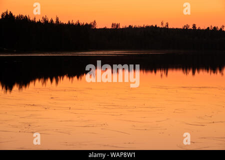 Intensive Sonnenuntergang über dem See in Finnland mit schönen Reflexionen Stockfoto