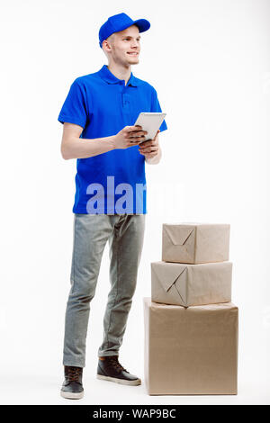 Mann in Lieferung arbeitet, hat drei Parzellen an seiner Seite als Er hält einen Tablet vor ihm. Stockfoto