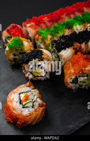 Sushi Roll Philadelphia mit Lachs, geräucherter Aal, Avocado, Frischkäse auf schwarzem Hintergrund. Sushi Menü. Japanisches Essen. Stockfoto
