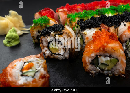 Sushi Roll Philadelphia mit Lachs, geräucherter Aal, Avocado, Frischkäse auf schwarzem Hintergrund. Sushi Menü. Japanisches Essen. Stockfoto