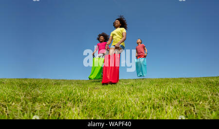 Kinder gunny Rennen in Taschen downhill auf der wiese gras Stockfoto