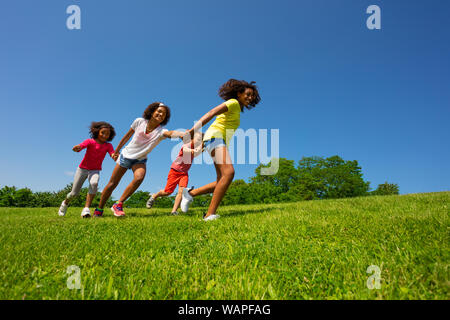 Jungen und Mädchen laufen schnell halten sich an den Händen an einem sonnigen Tag Stockfoto