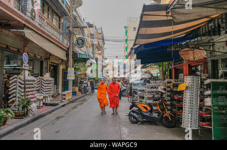 Bangkok, Thailand - 15. Dezember 2017: Szene von zwei Buddhistische Mönche auf einer Straße in Bangkok mit Geschäfte, kleine Restaurants und ein Tempel am Ende Stockfoto