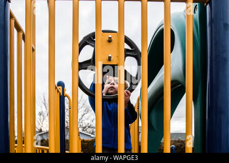 Kind auf dem Spielplatz spielen neugierig an Lenkrad suchen Stockfoto